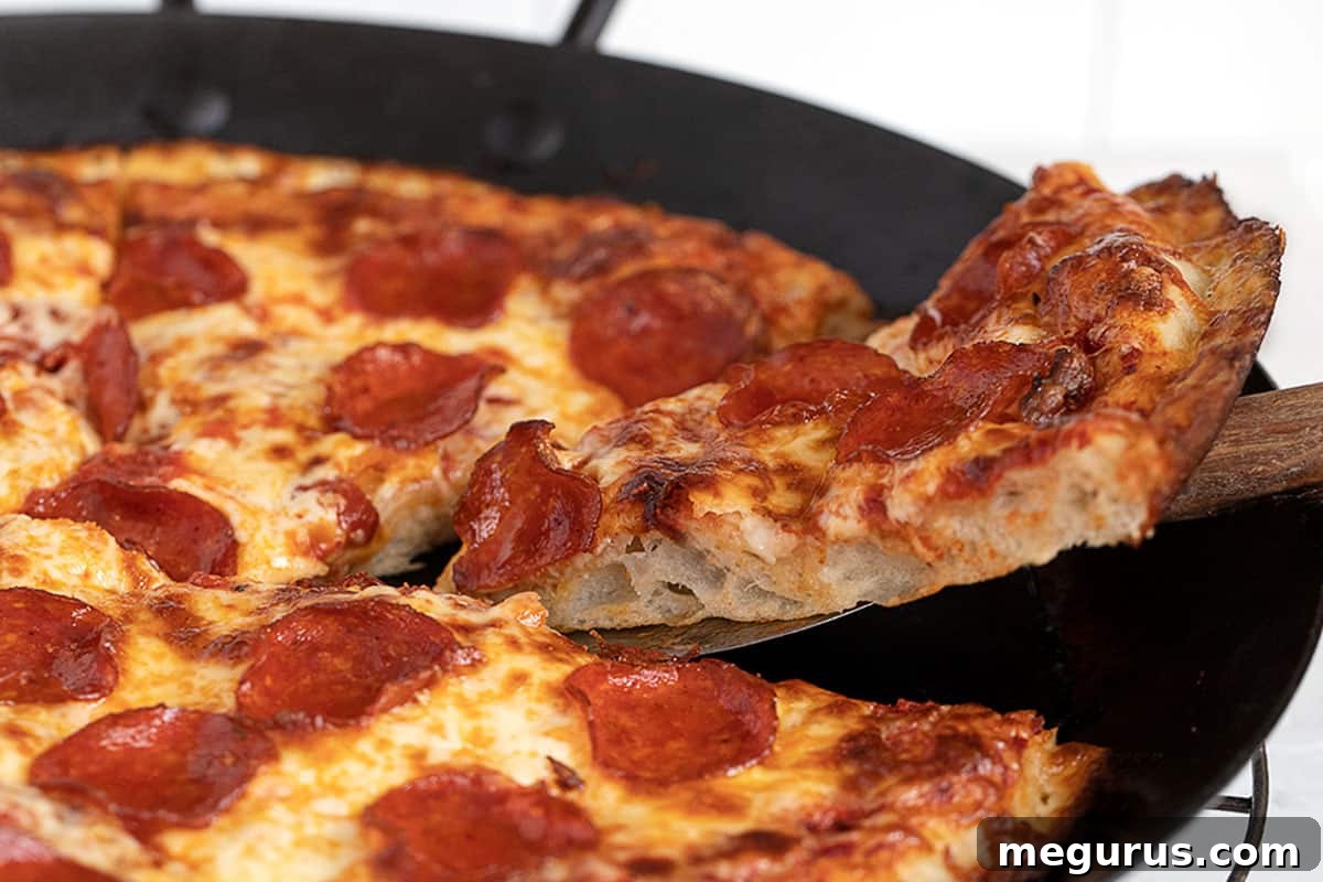 pan pizza sliced in pan, showcasing its thick, golden crust and melted cheese