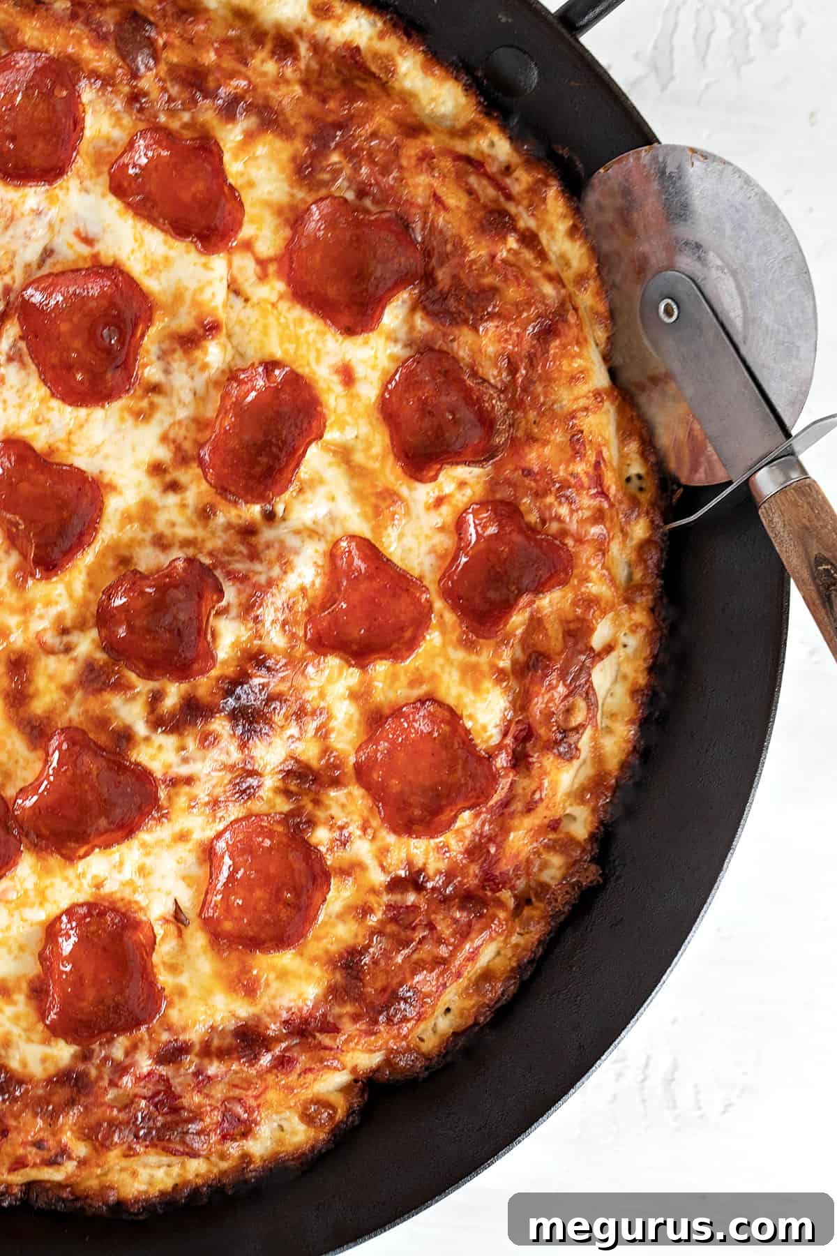 close-up of pan pizza sliced in pan, showing crispy edge and melted cheese