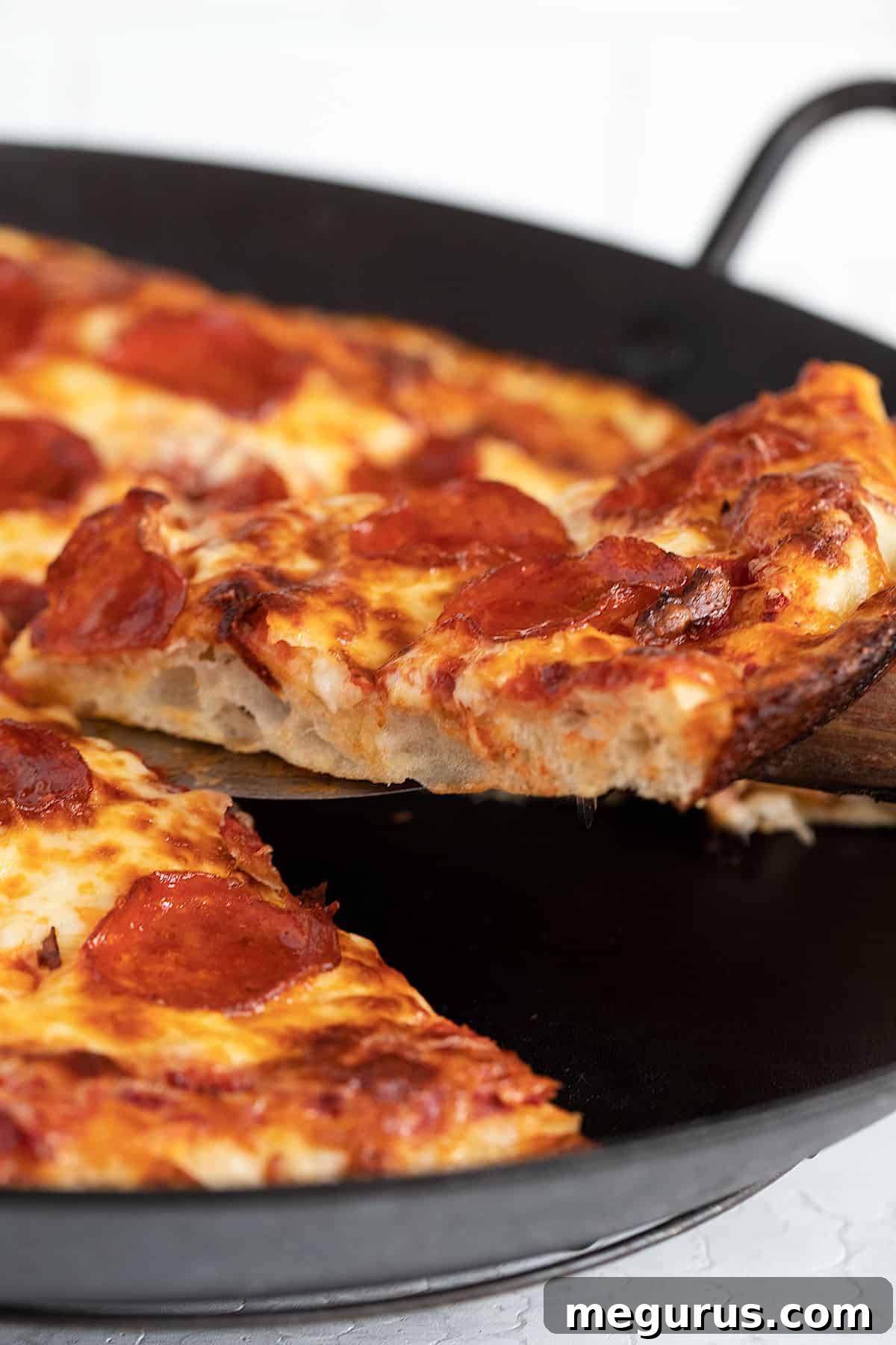pan pizza sliced on a wooden board, with a focus on its appealing crust and toppings