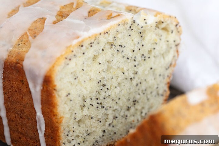 A freshly baked lemon poppy seed loaf, perfectly sliced and arranged on a cooling rack, ready to serve.