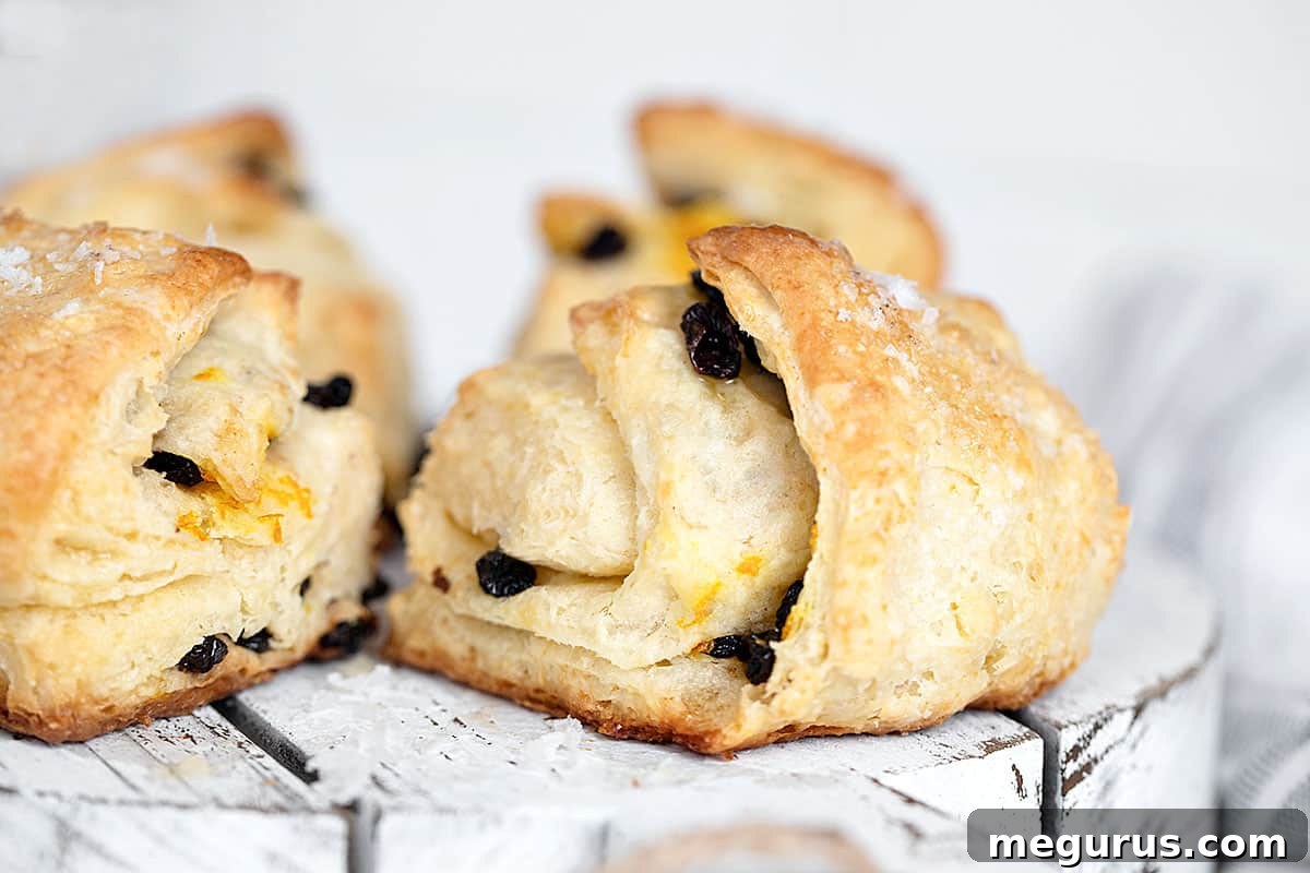 Golden brown Irish scones with currants and a sprinkle of orange zest, served on a rustic wooden board.