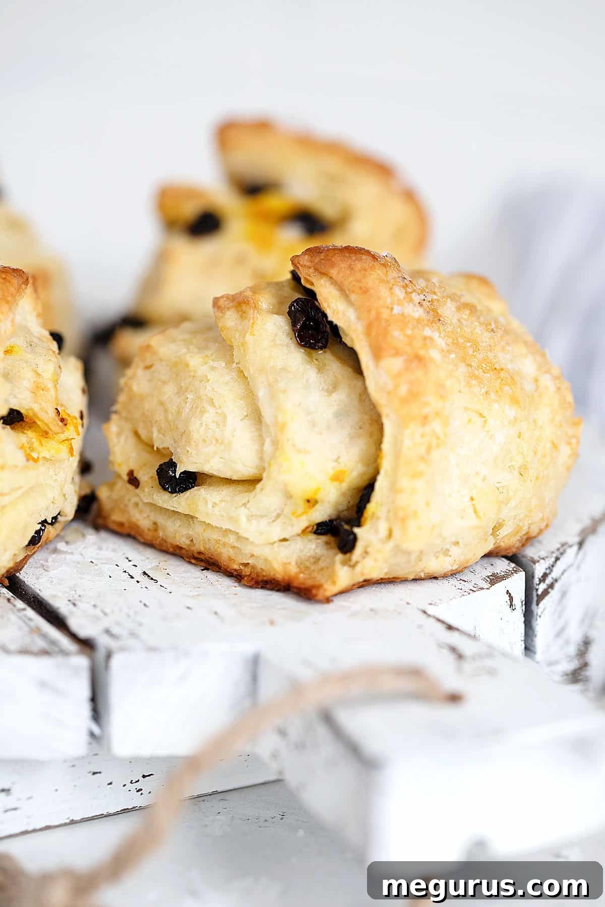 A close-up of a stack of freshly baked Irish scones, glistening with melted butter and sprinkled with flaky salt, on a wooden serving board.