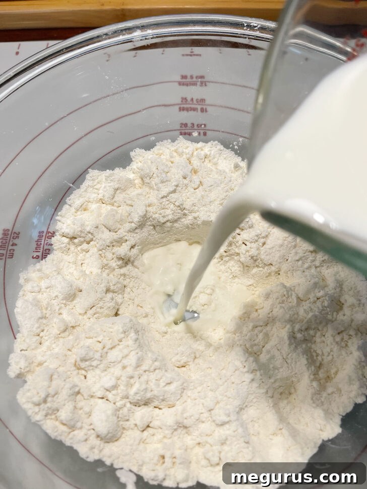 Pouring the milk mixture into the flour and butter mixture in a bowl.