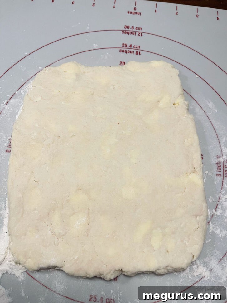 Pressing the scone dough into a rectangular shape on the work surface.