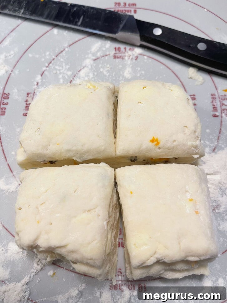 Cutting the folded scone dough into four equal square portions using a sharp knife.
