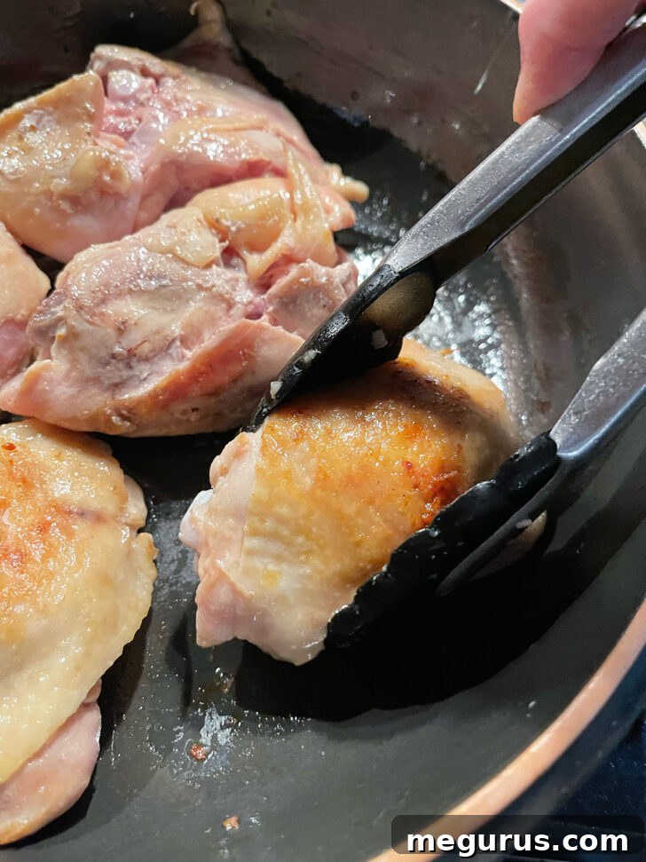Browning chicken thighs in a skillet.