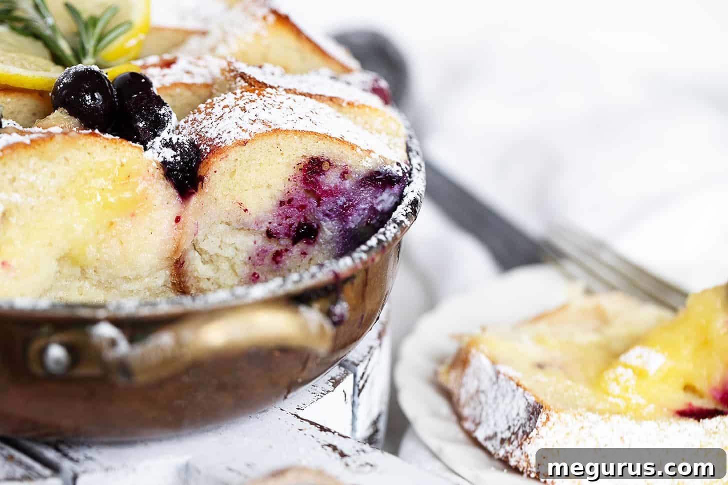 Blueberry lemon bread pudding in baking dish and spooned out onto a plate.