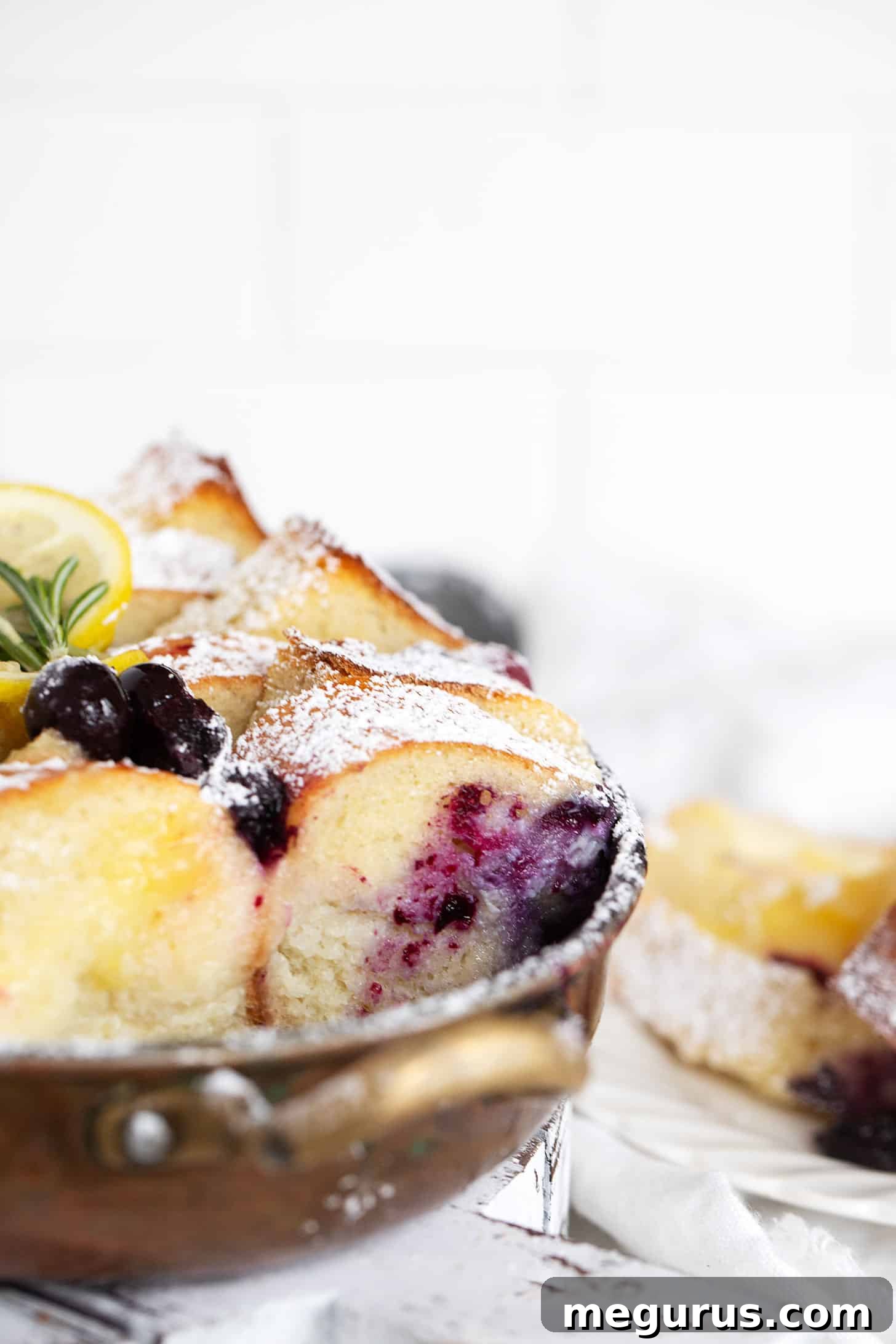 Blueberry lemon bread pudding in baking dish and spooned out onto a plate.