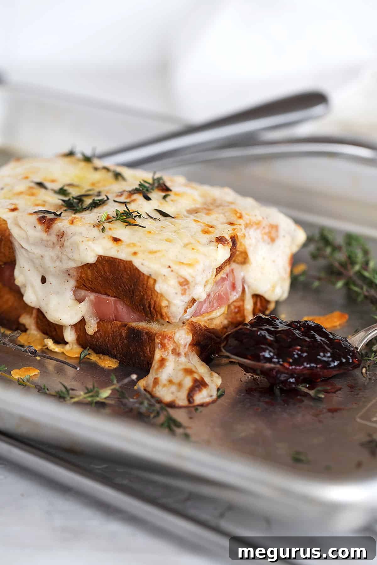 Golden Croque Monsieur sandwiches ready to serve, with a spoonful of raspberry jam