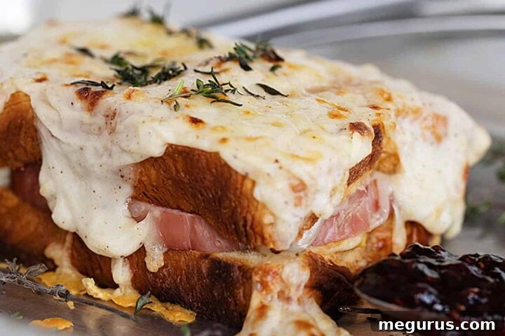 Croque Monsieur on baking sheet with raspberry jam on spoon