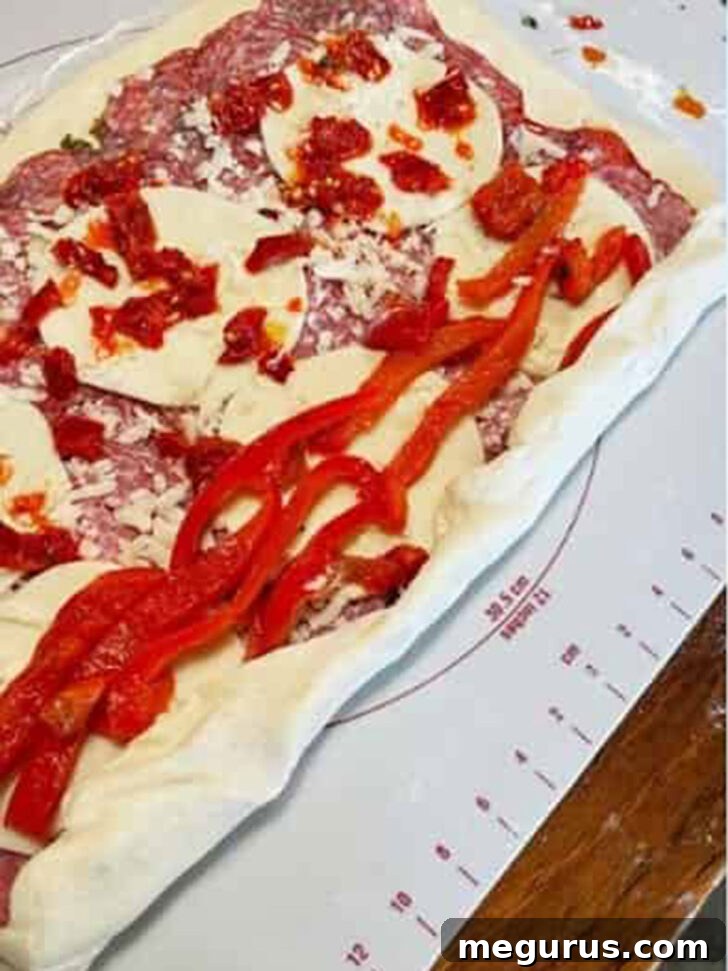 Beginning the rolling process of the stromboli, starting from one long edge to create a compact log.