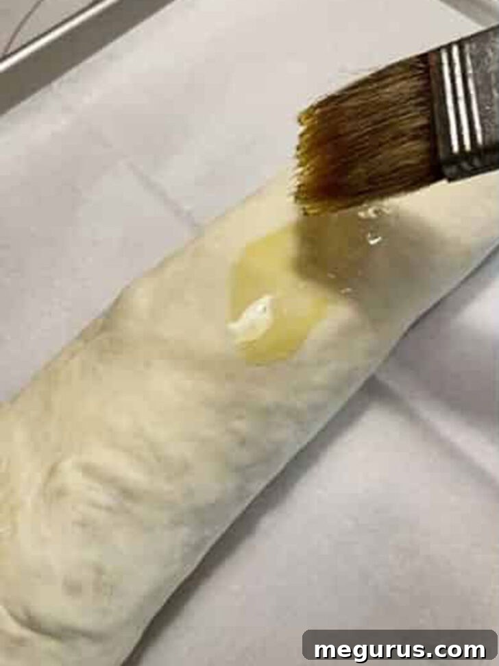 Brushing the top of the stromboli dough with an egg wash for a golden, glossy crust.