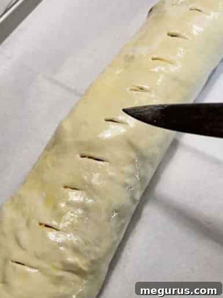 Making small, strategic slits in the top of the stromboli to allow steam to escape during baking.