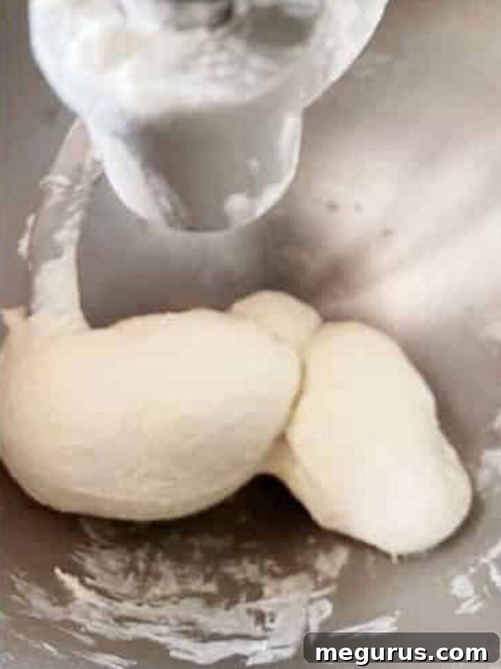Finished homemade stromboli dough in a stand mixer, perfectly kneaded and ready for the first rise.