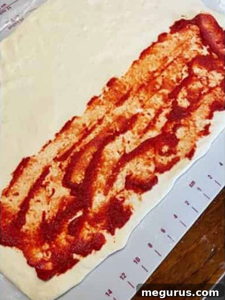 Tomato paste evenly spread over half of the stromboli dough, forming a flavorful base.