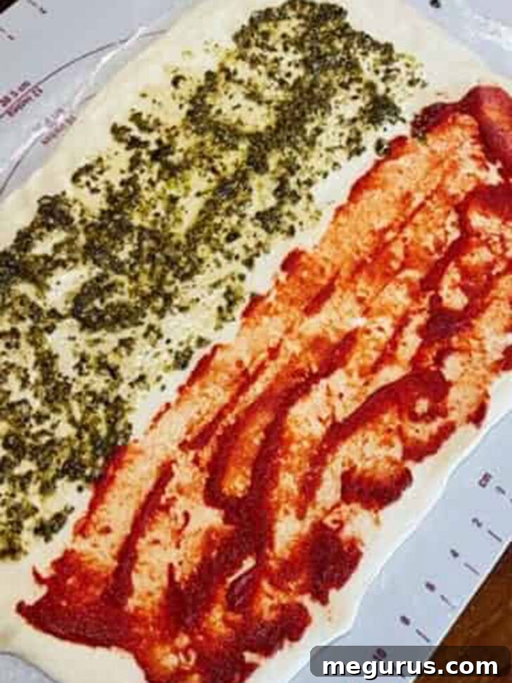 Smoothly spread pesto covering the second half of the stromboli dough, creating a dual flavor foundation.