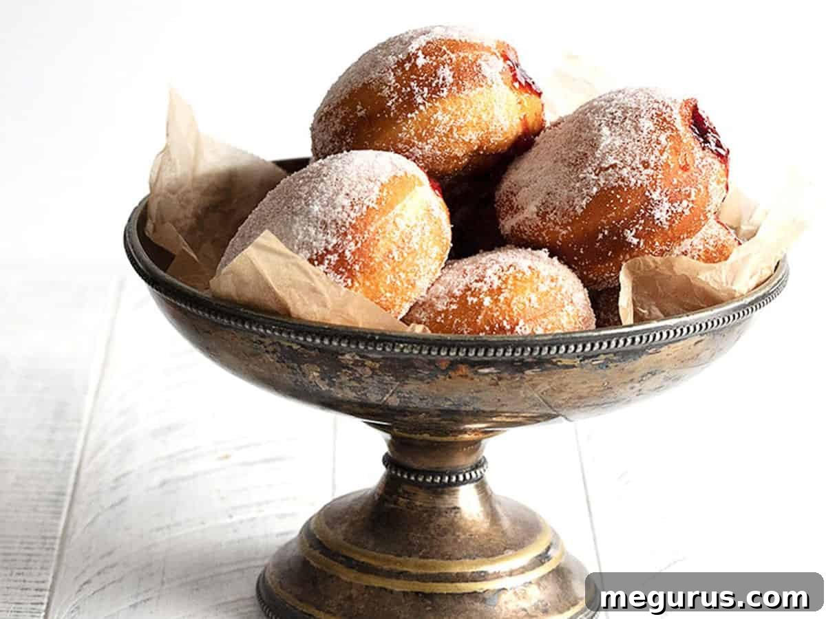 A stack of golden-brown, sugar-dusted authentic Polish paczki, ready to be enjoyed.