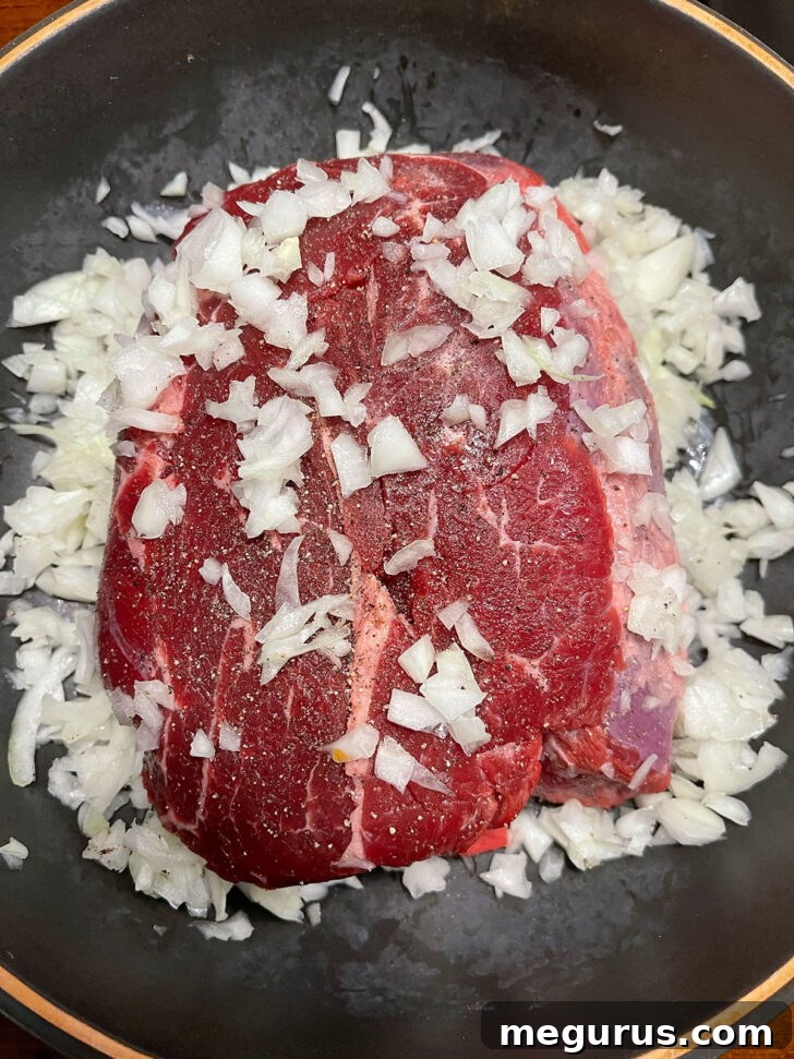 Beef and onion in cooking dish.