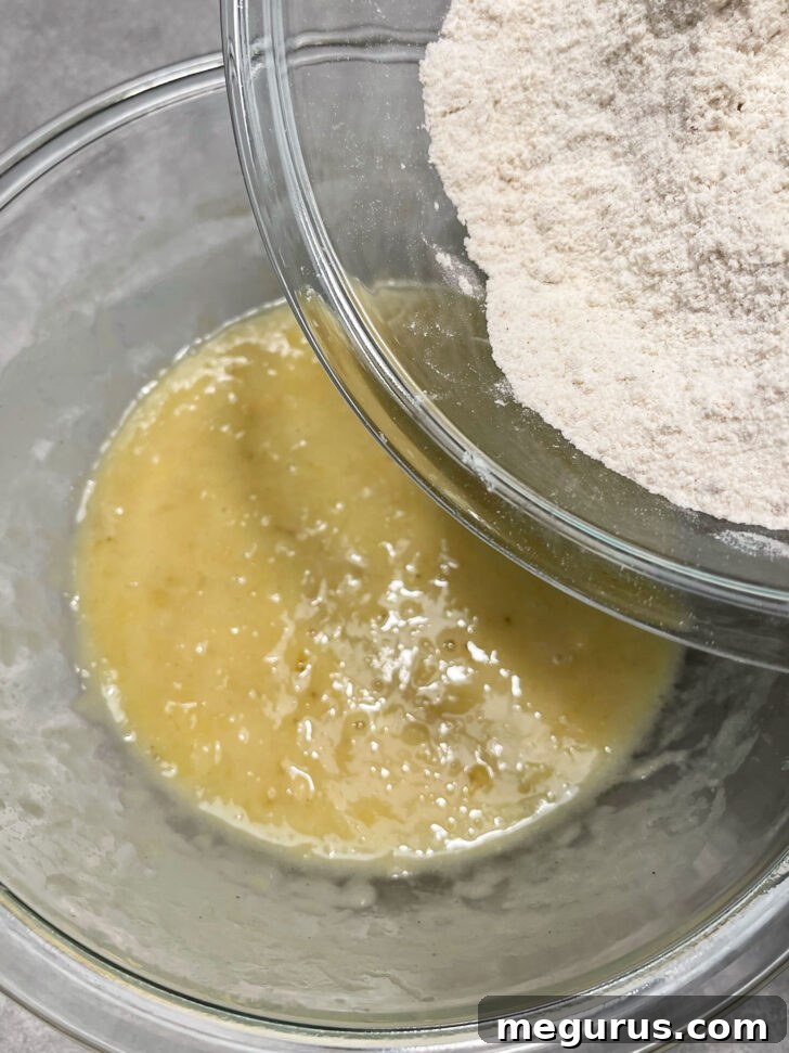 Dry ingredients being gently folded into the wet ingredients for banana muffin batter.