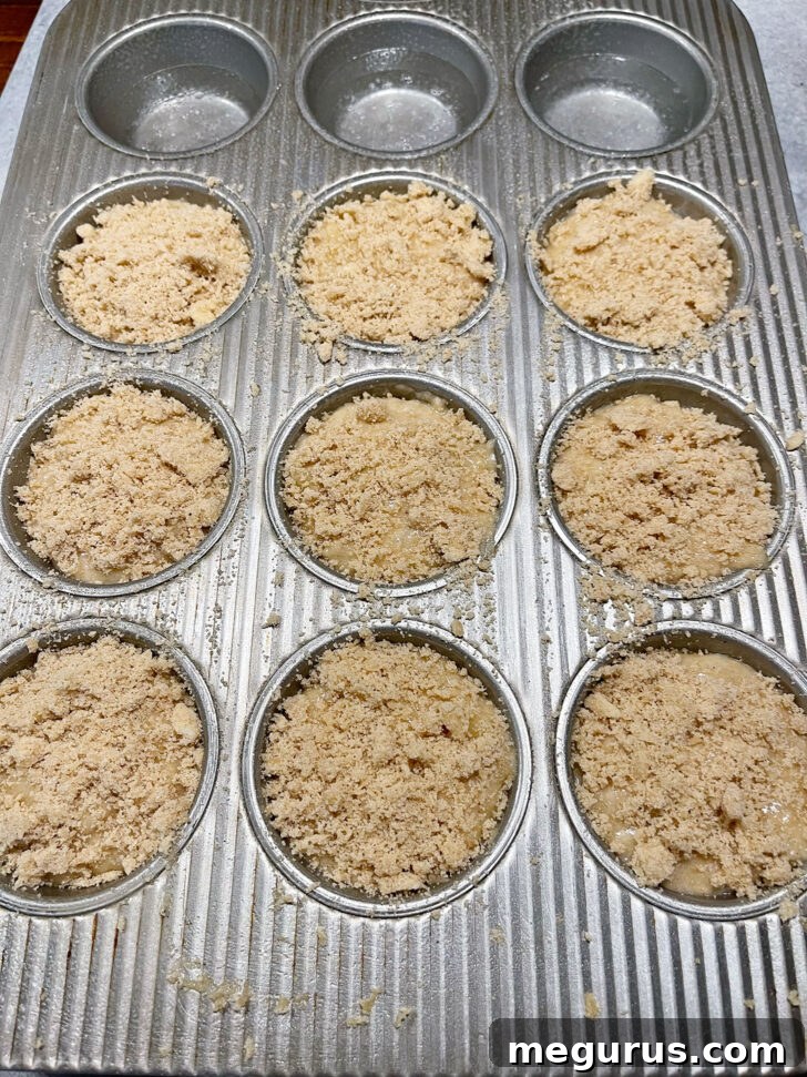 Muffin batter topped with a generous amount of crumb topping before baking.