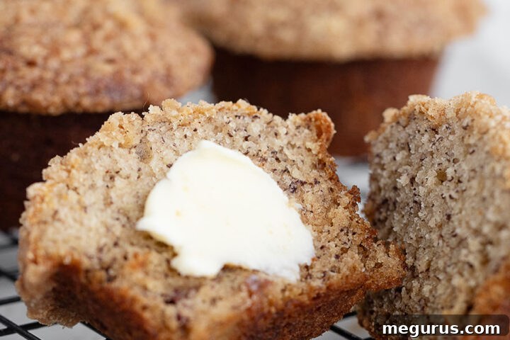 Banana crumb muffins on cooling rack split with butter.