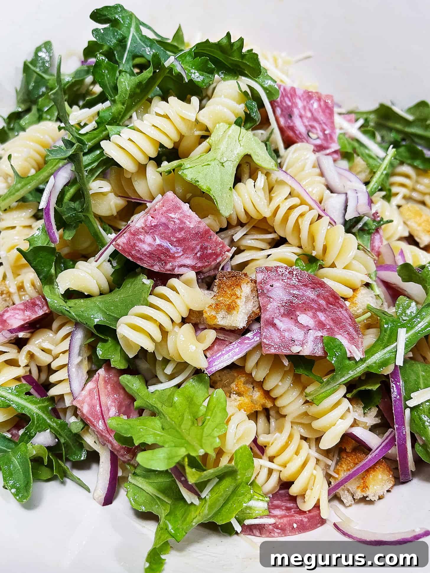 Pasta salad with salami in a bowl.