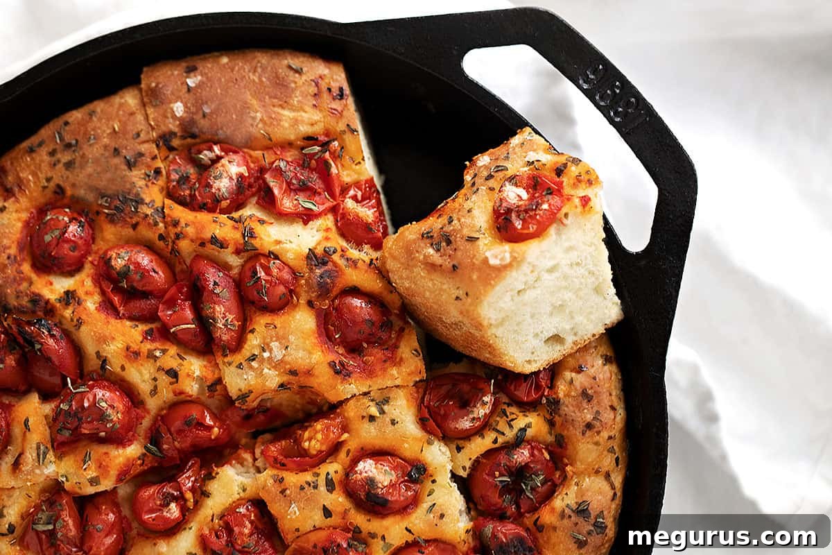 Skillet focaccia sliced in cast iron skillet, golden brown and ready to serve