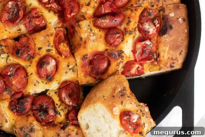 Skillet focaccia sliced in cast iron skillet, golden brown and garnished