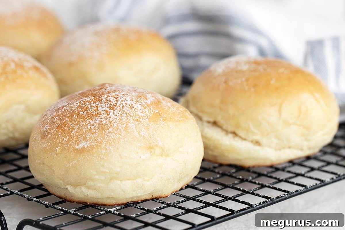 Freshly baked soft potato hamburger buns cooling on a wire rack, ready to be enjoyed.