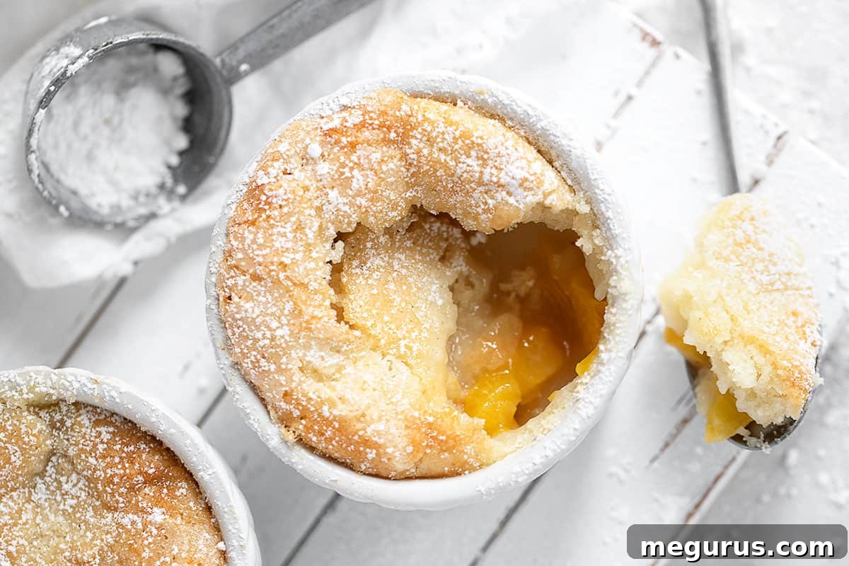 Warm peach pudding cake in a white ramekin, ready to be enjoyed with a spoon.