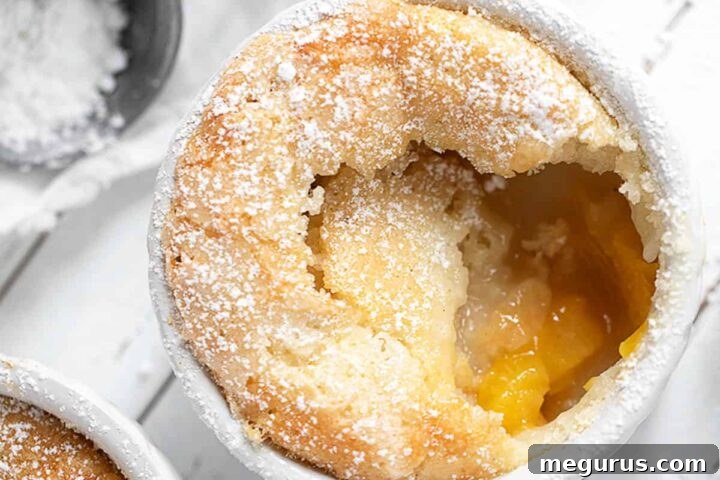 Peach pudding cake in a white ramekin with a spoon, showing a golden crust and soft interior.