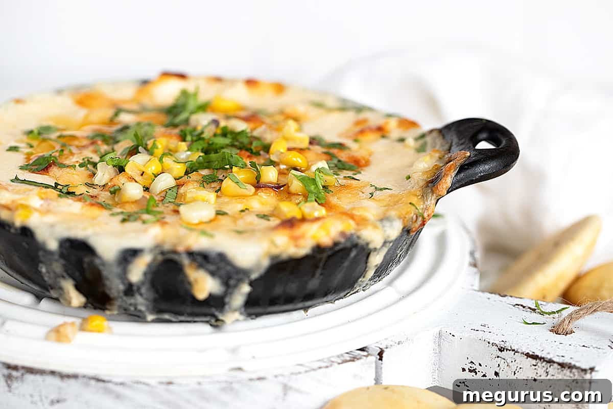 Hot Cheesy Corn Dip in a cast iron pan with golden baked pita rounds, ready for serving