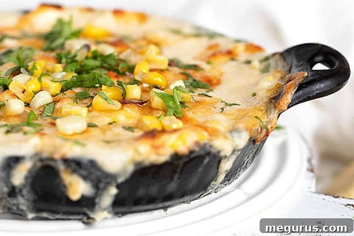 Hot corn dip in cast iron pan with baked pita rounds