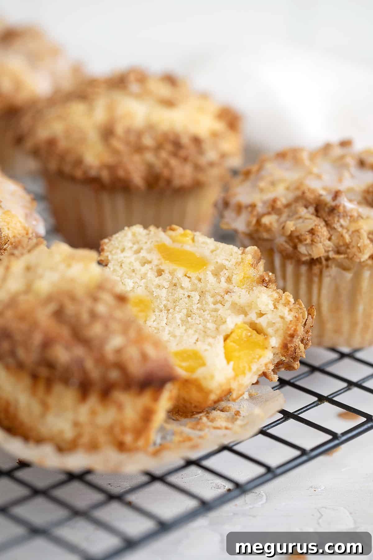 Close-up of peach crisp muffins on a cooling rack, showing the golden-brown crumble and soft muffin texture.