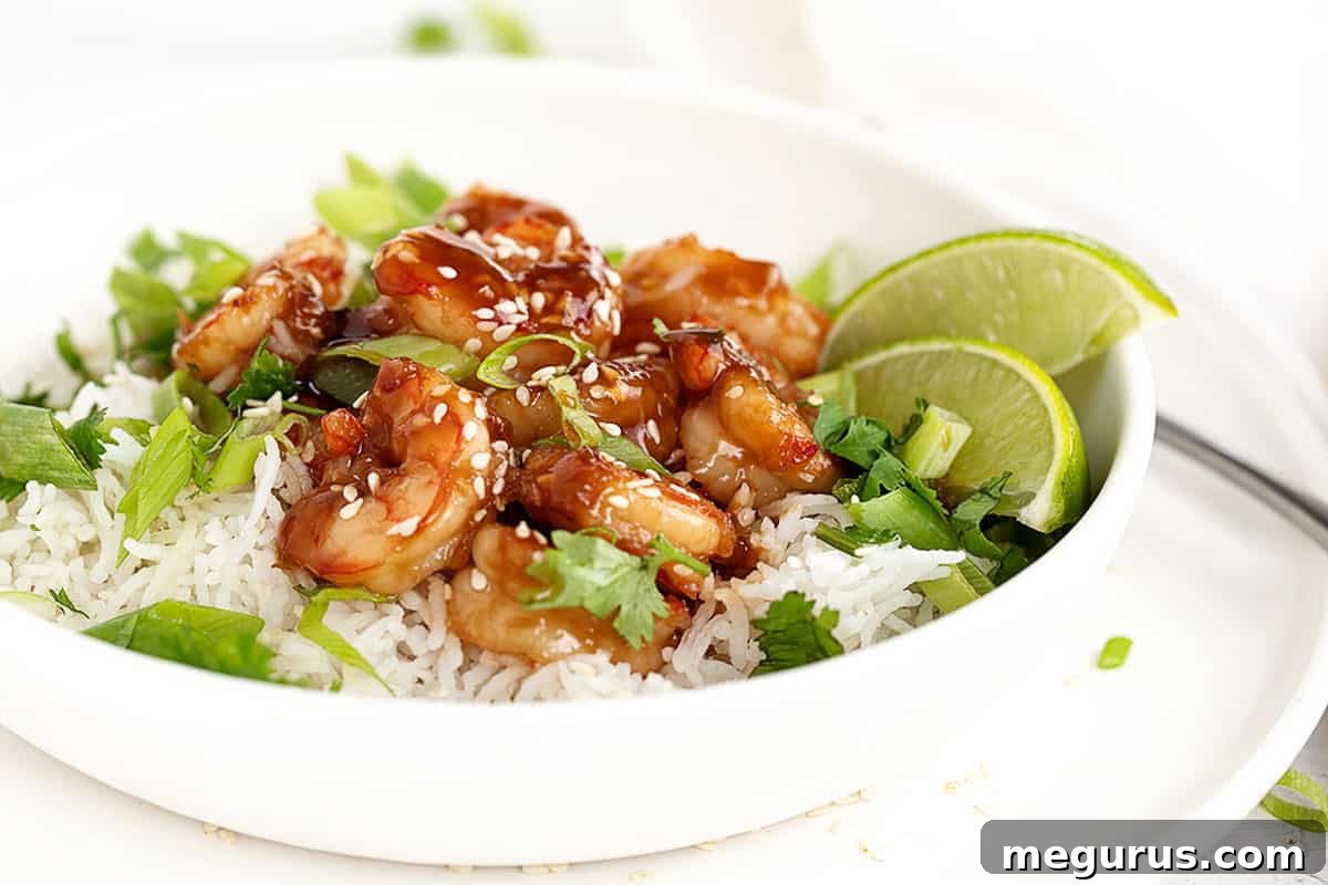 Irresistible Honey Garlic Shrimp served in a bowl with fluffy white rice, garnished with fresh green onions.