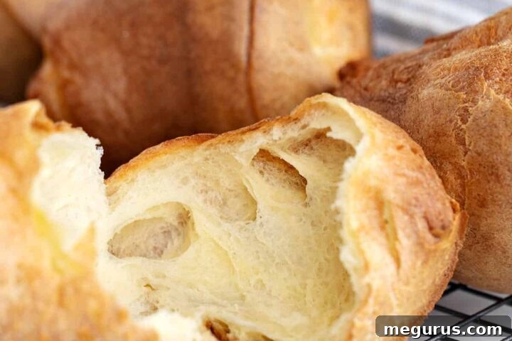 Freshly baked popovers on a cooling rack, one split open