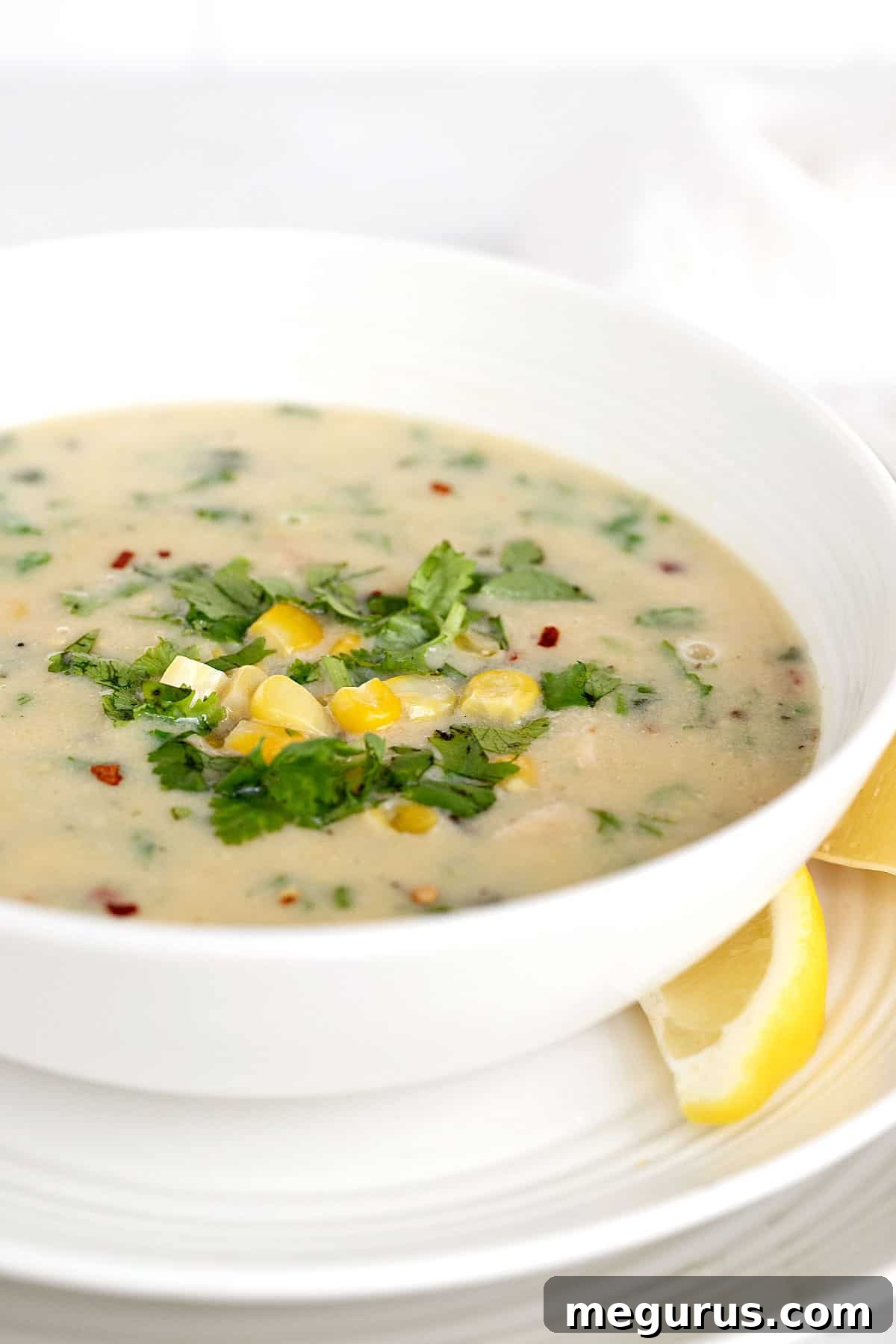 finished chicken corn coconut soup in white bowl, garnished with cilantro