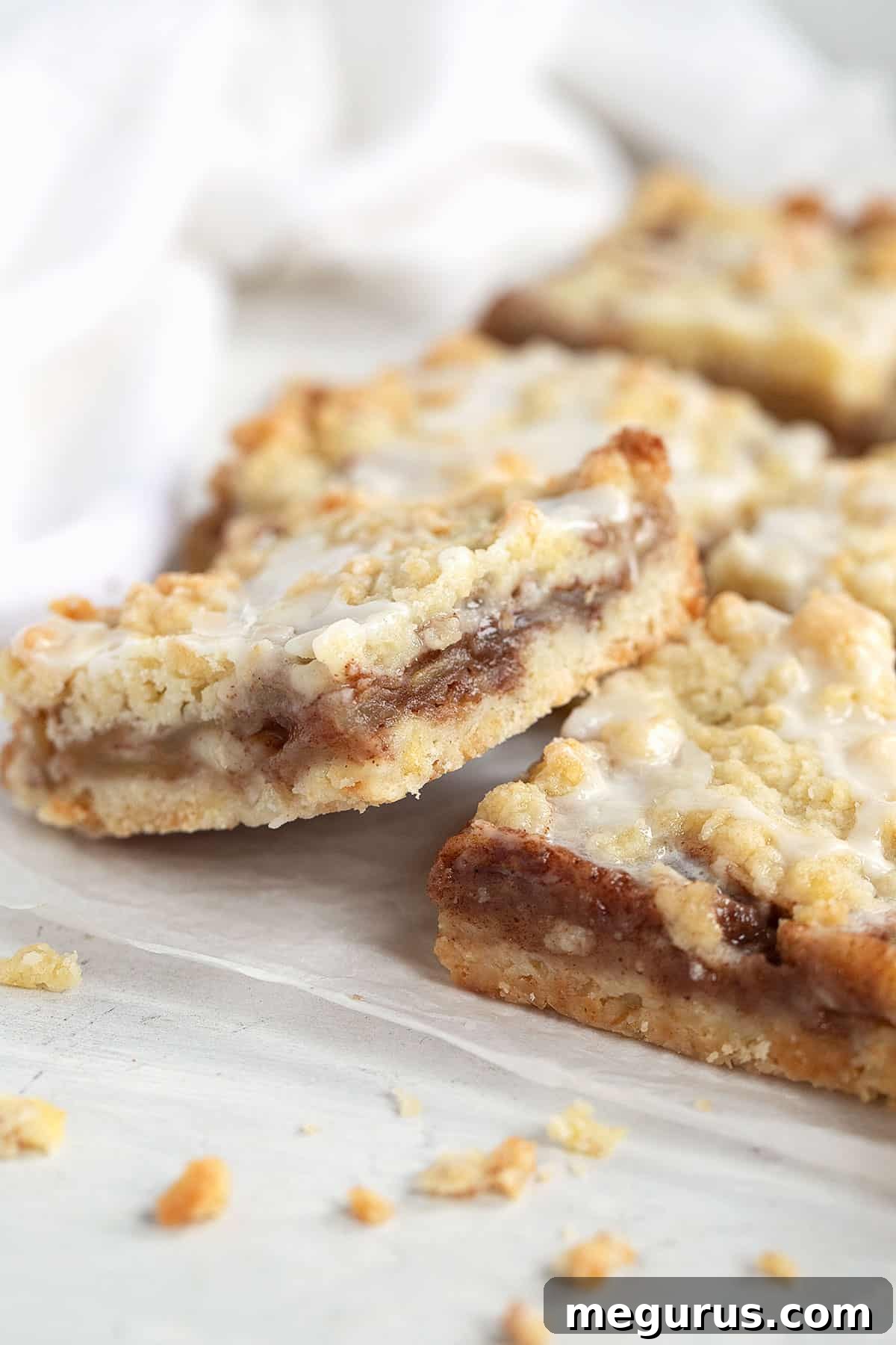 Perfectly cut apple streusel bars resting on parchment paper after cooling.