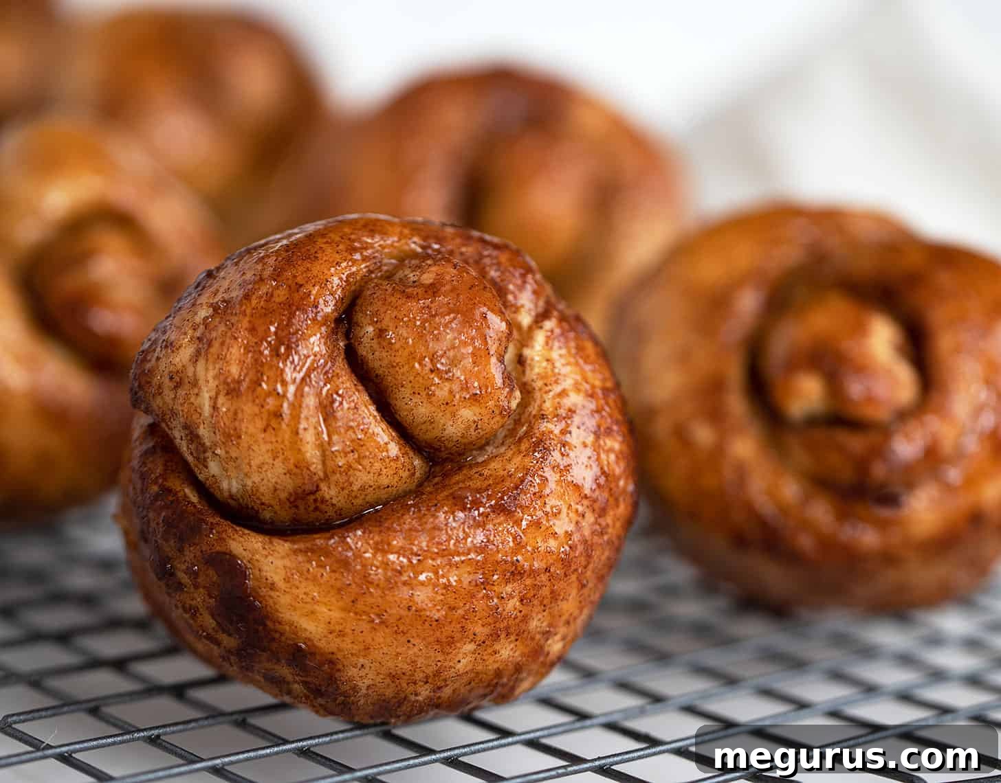 Irresistible sticky cinnamon knots glistening with brown sugar glaze on a cooling rack