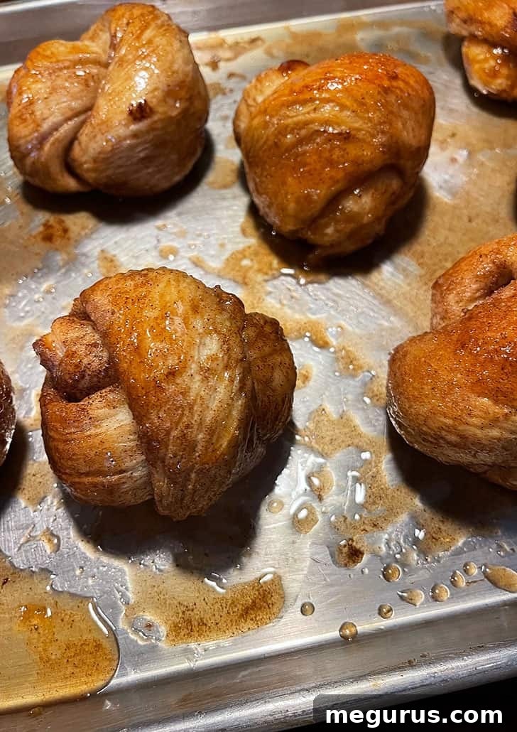 Baked cinnamon knots freshly out of the oven, golden brown and bubbling with glaze