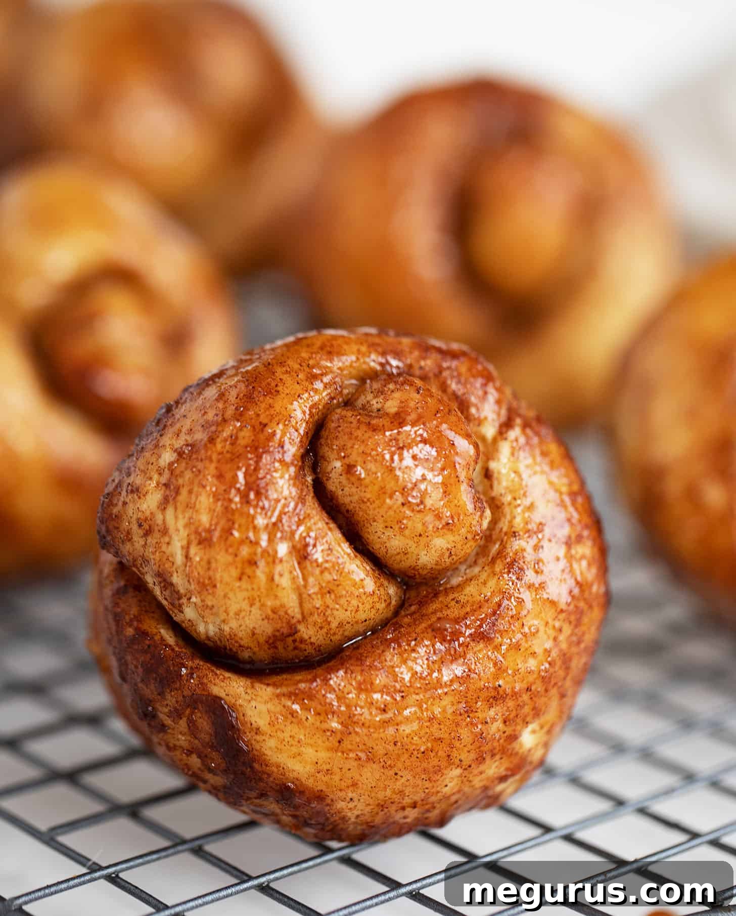 Close-up of sticky cinnamon knots on a cooling rack, glistening with a generous layer of brown sugar glaze