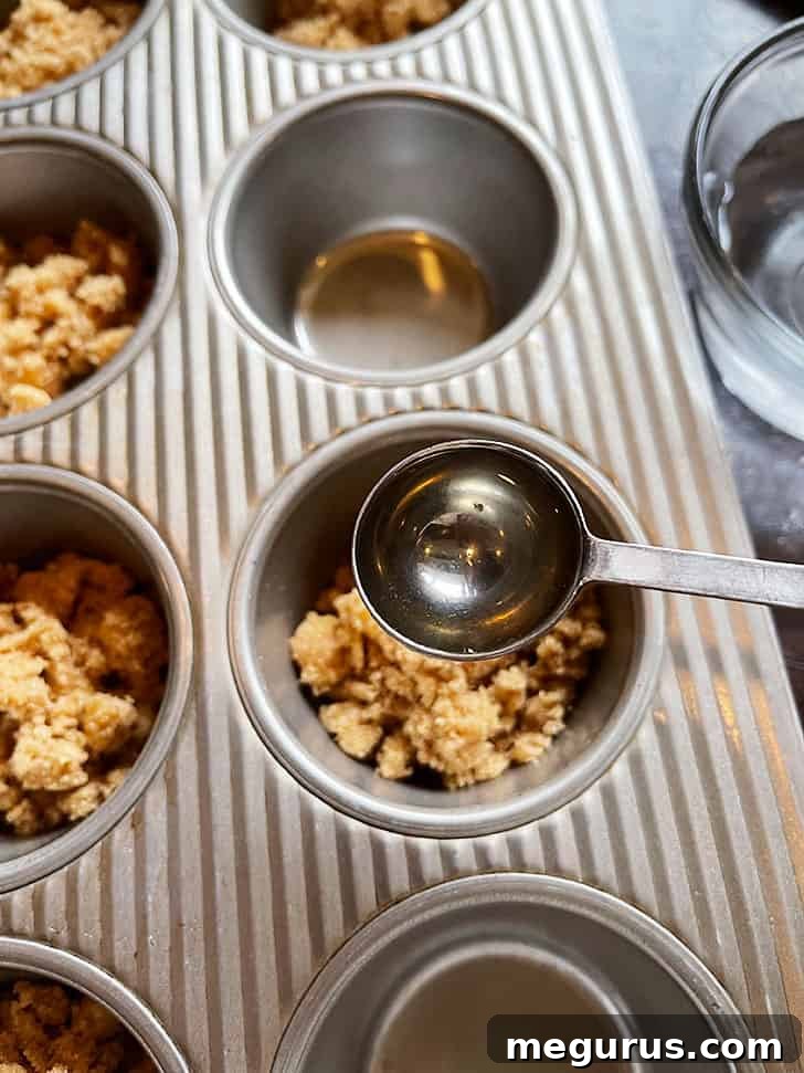 Adding water to the brown sugar, cinnamon, and butter mixture in muffin cups