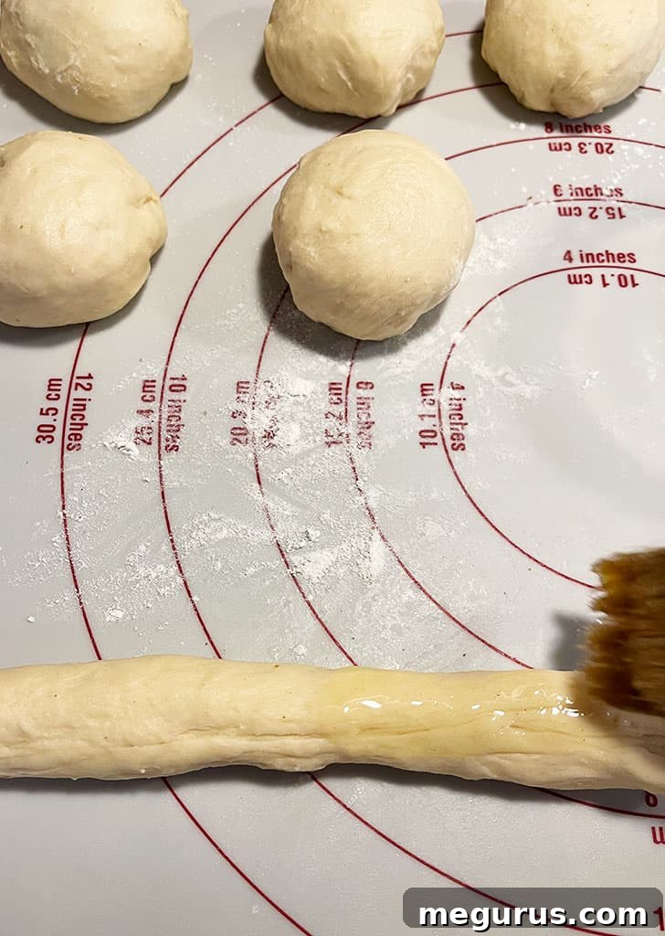 Dough rope being brushed generously with melted butter before coating