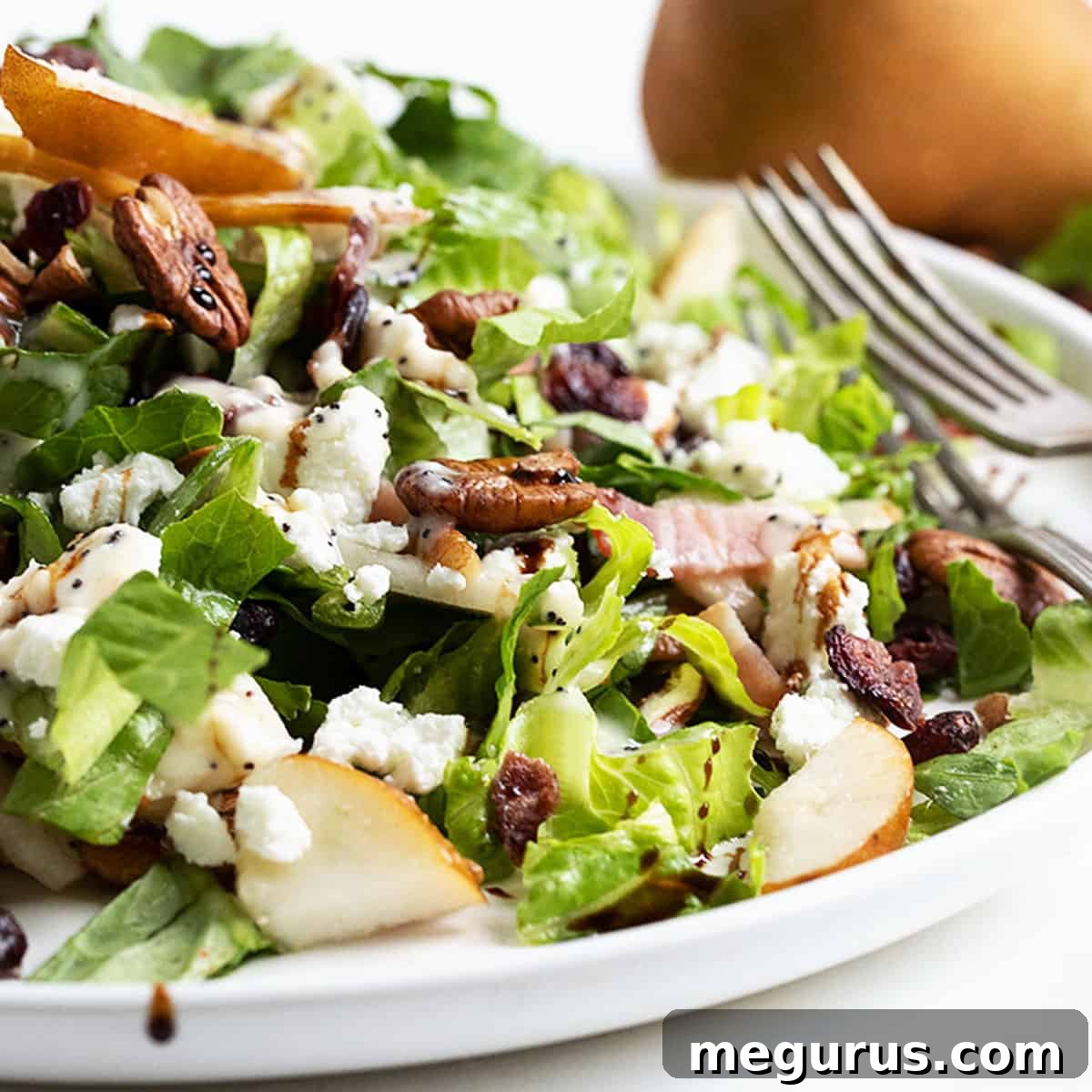 Fall pear chopped salad on white plate with pear behind