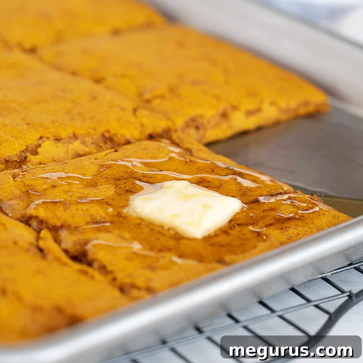 sheet-pan pumpkin pancakes in pan with maple syrup and butter