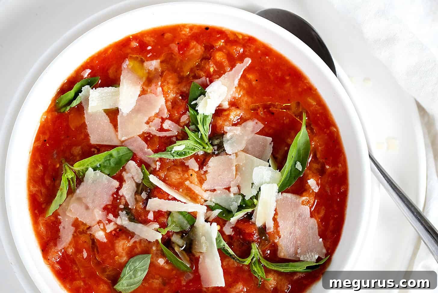 A steaming bowl of Tuscan Tomato Bread Soup (Pappa al Pomodoro) garnished with fresh basil and a drizzle of olive oil, ready to be enjoyed.
