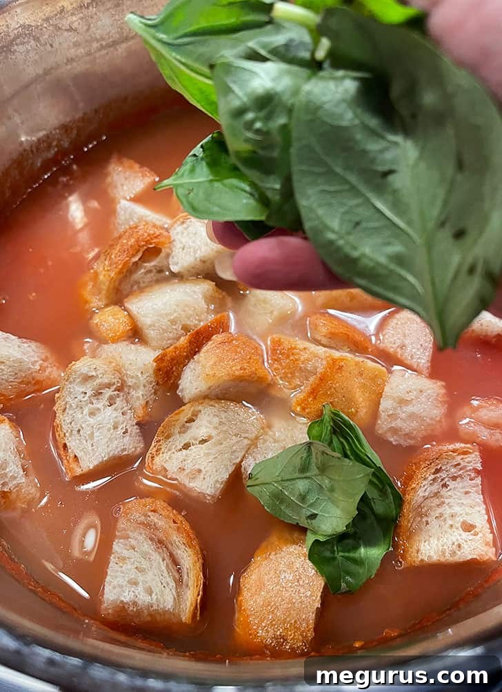Fresh basil leaves being added to the simmering Tuscan Tomato Bread Soup.