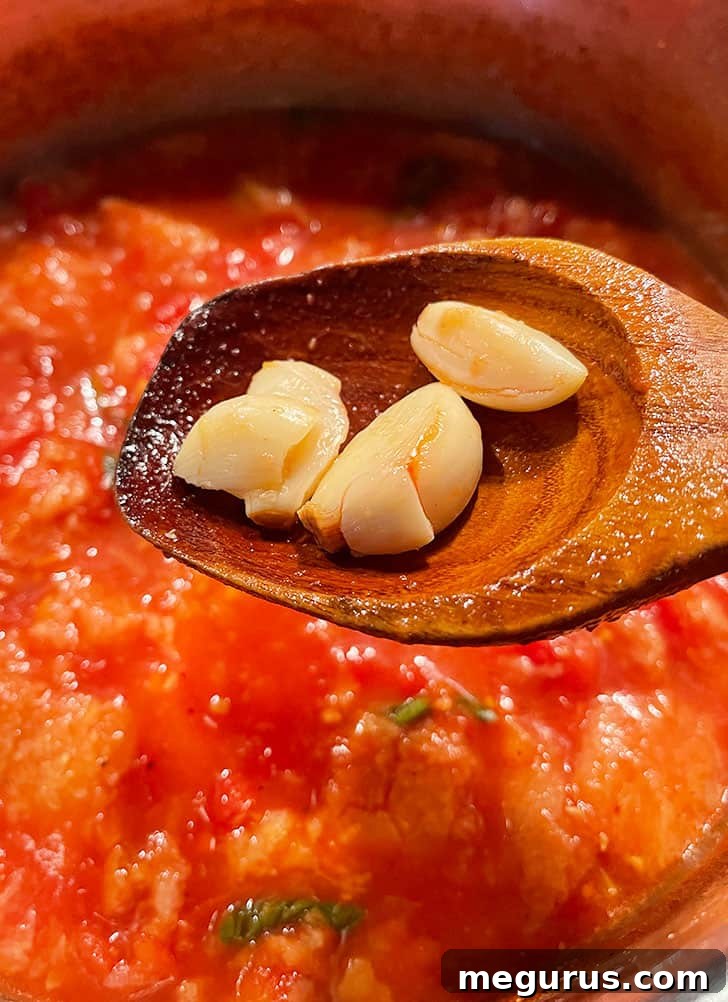 Garlic cloves being carefully removed from the cooked Pappa al Pomodoro soup.