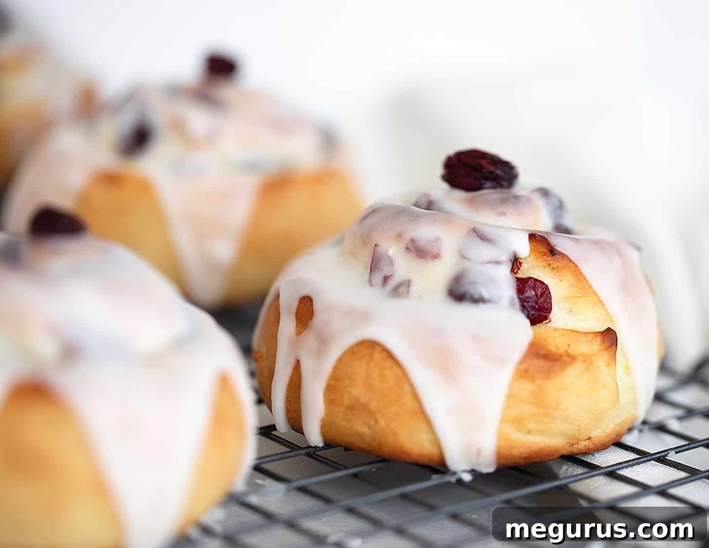Soft and tender cranberry lemon buns with a sweet lemon glaze on a cooling rack