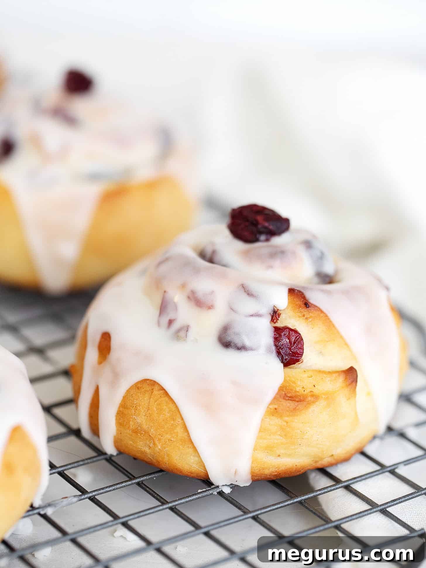 Close-up of cranberry lemon buns on a cooling rack, showing their soft texture